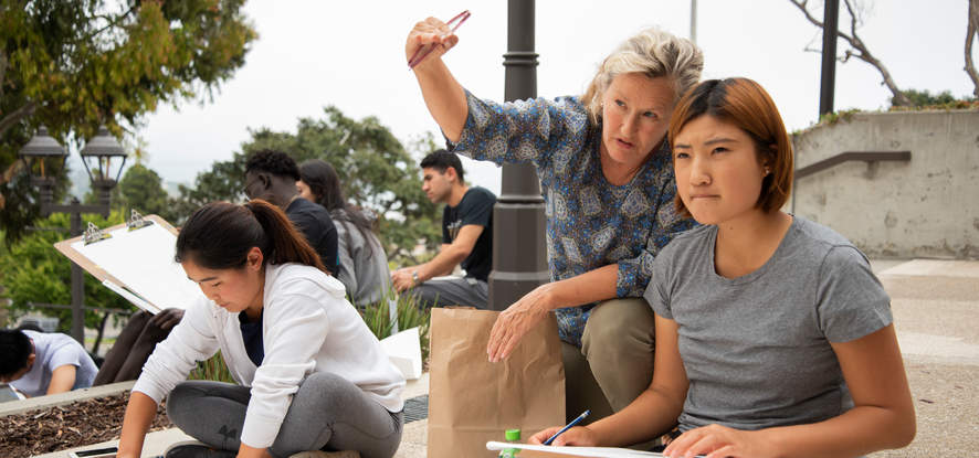 Pepperdine professor teaching an art class outside, conversing closely with a student as she points out something in the distance