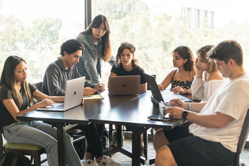 Students studying at a table with laptops open