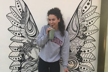 Seaver student Grace Cummins pictured in front of a wall with wings