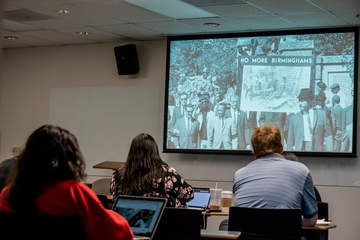 Students looking at a black and white photo in a history classroom