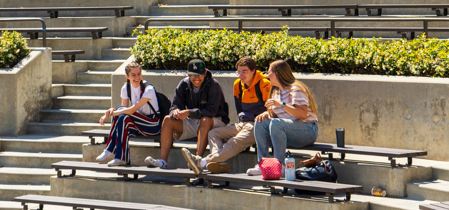 Four students sitting in the amphitheatre, talking
