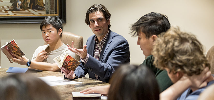 students with professor discussing a book