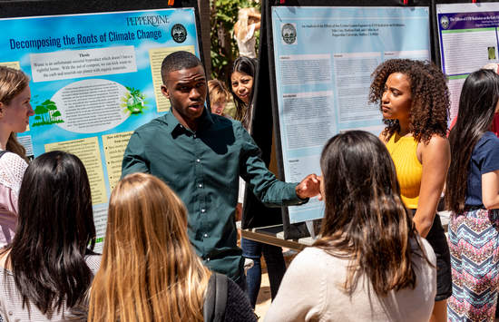 Seaver students gathered around a student presenting his poster presentation on the Roots of Climate Change