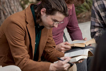 Male student reading a book during an outside class session