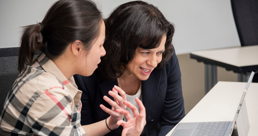 Female student and Seaver professor looking at a laptop in a classoom