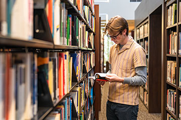 student looking at a book in the library