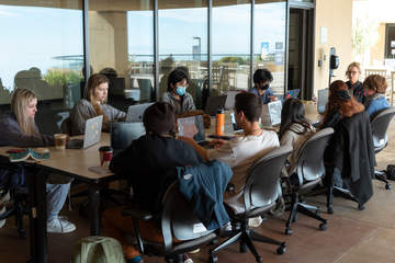 Students with open laptops having class outside