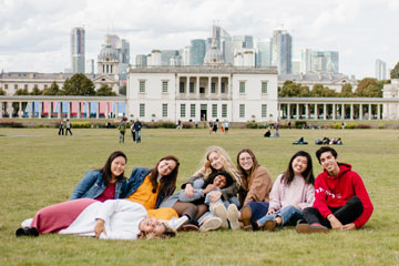 Seaver students pictured sitting in a park with a London skyline behind them