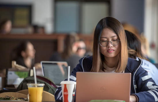 Female student with glasses looking at a laptop