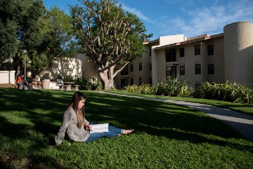 Student reading a book outside Seaside residence hall