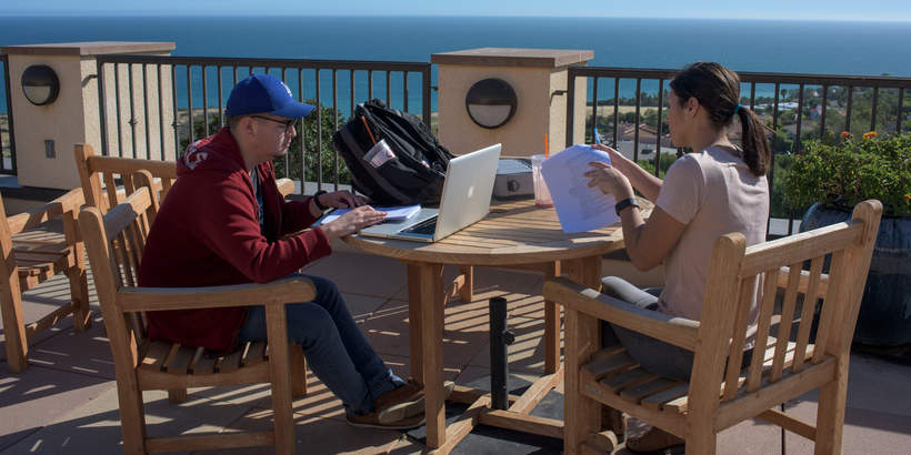 Two students sitting at the Sandbar Cafe overlooking the Pacific Ocean