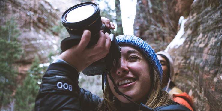 Image of a female student with a camera taking a photo of rocks in a canyon