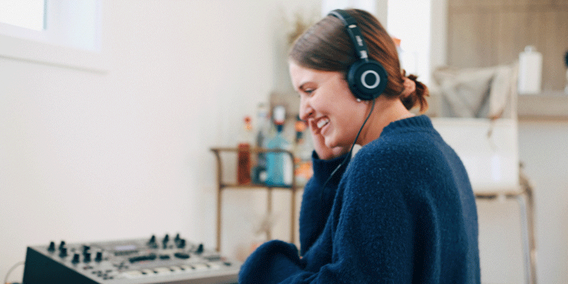 Seaver student smiling, listening to a sound board via headphones