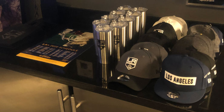 LA Kings baseball caps, tumblers, and brochures arranged on a desk