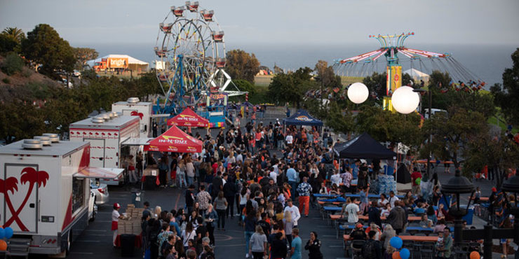 Aerial shot of In N Out trucks, a crowd of people, and a ferris wheel at Waves Weekend