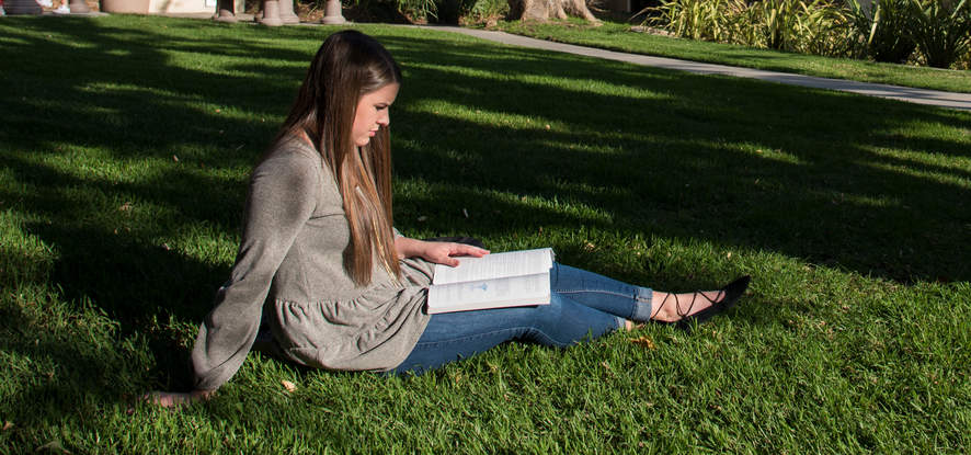 Seaver student zittend op het gras een boek te lezen