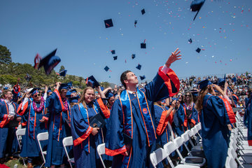 Students tossing a grad cap