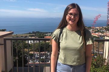 Katherine Bacino pictured at the Malibu campus wearing a green shirt, blue jeans, and glasses