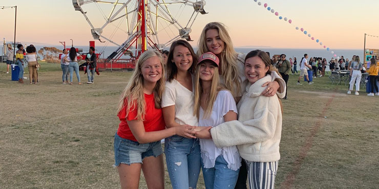 Katie White pictured with friends in front of a ferris wheel on Alumni Park