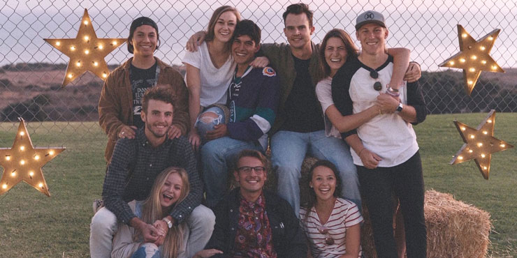 Katie White pictured with fellow Seaver students in front of a fence with light up stars