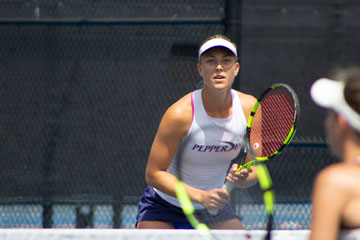 Ashley Lahey on the tennis court, grasping her racquet, concentrated on her opponent opposite the net
