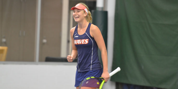 Ashley Lahey, smiling, with one hand in a fist and the other grasping her tennis racquet