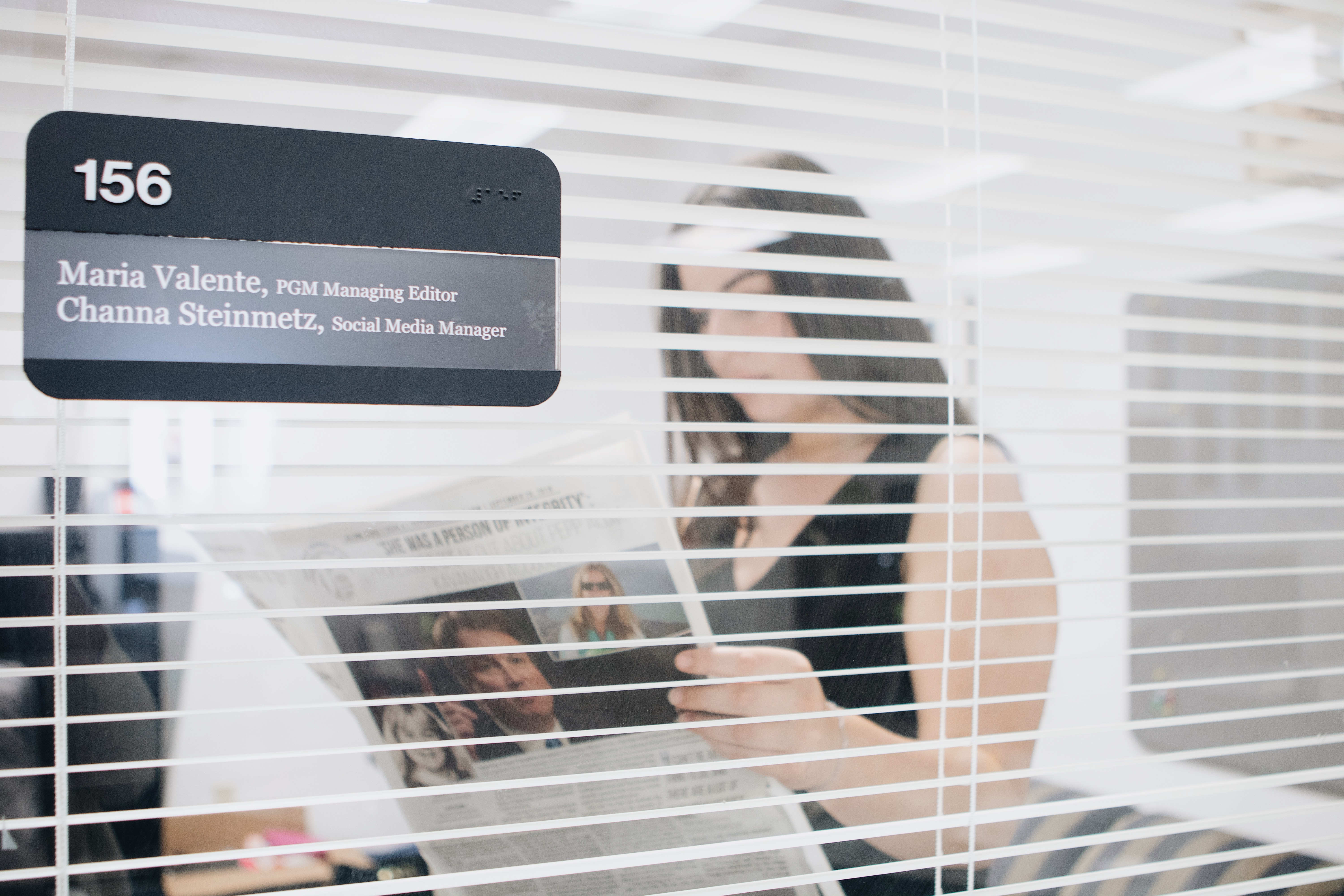 Maria Valente viewing a Graphic newspaper through a window lens