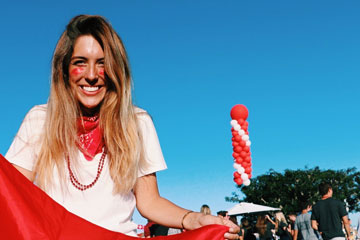 Seaver senior Millie Vieira photographed holding a red flag, wearing a white t-shirt and a red bandana