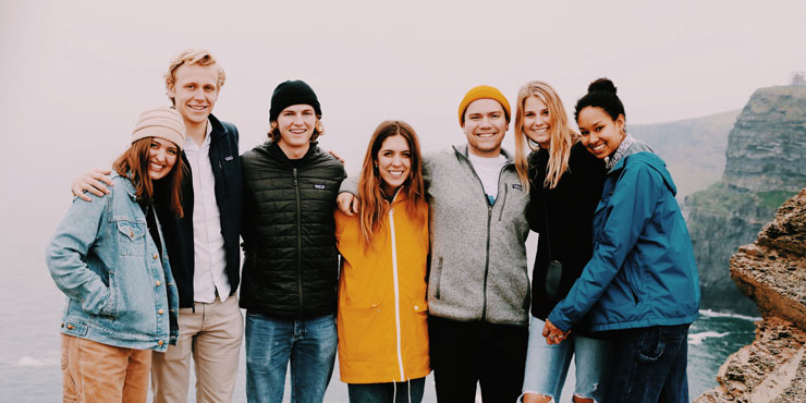 Millir Vieira pictured amongst Seaver students on a cliff overlooking a body of water