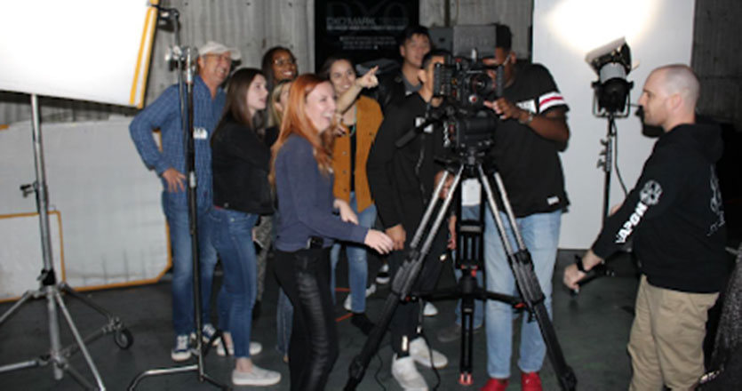 Seaver students gathered around a film camera at RED Studios