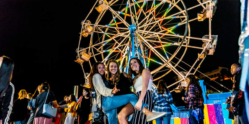 Students posing in front of a ferris wheel 