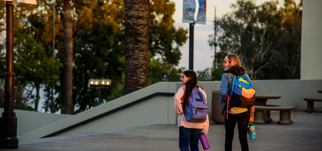 Two students walking on campus carrying backpacks