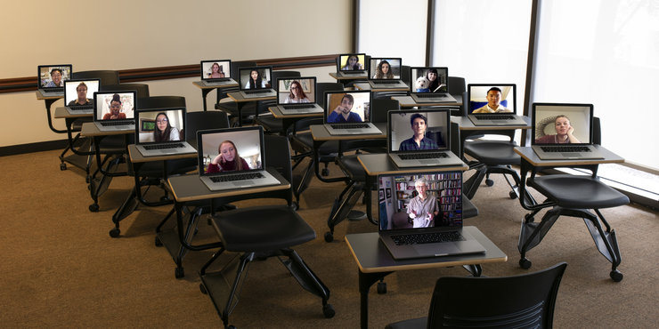 Students on a laptop screen in a classroom doing remote learning