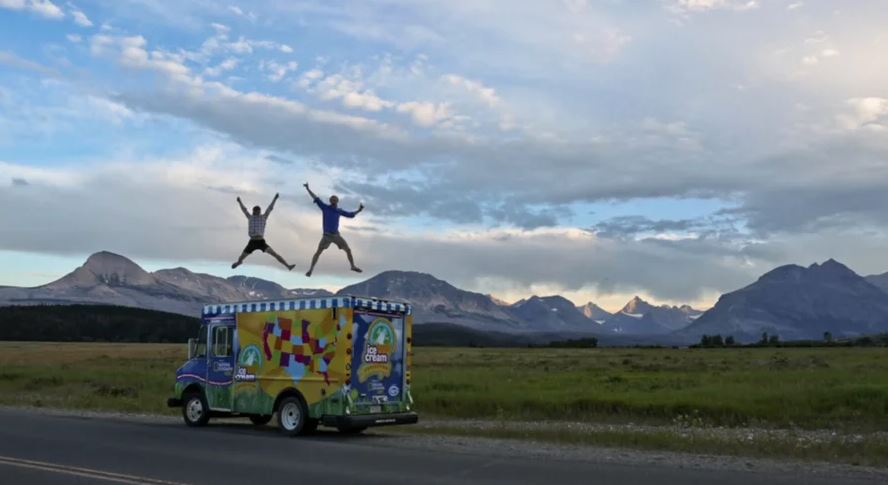Two men jumping on top of a ice cream truck