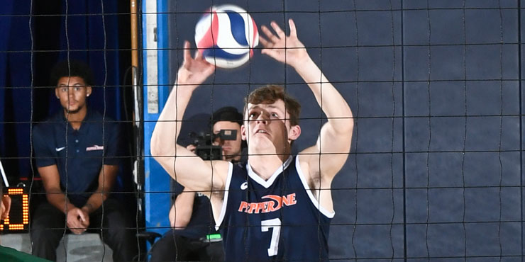 Spencer Wickens on the volleyball court, palms open, about to serve a volleyball over the net