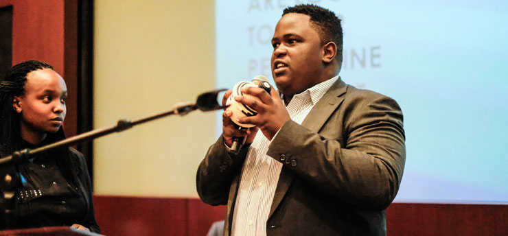 Male, Seaver student holding a mic and speaking to a room at Seaver College