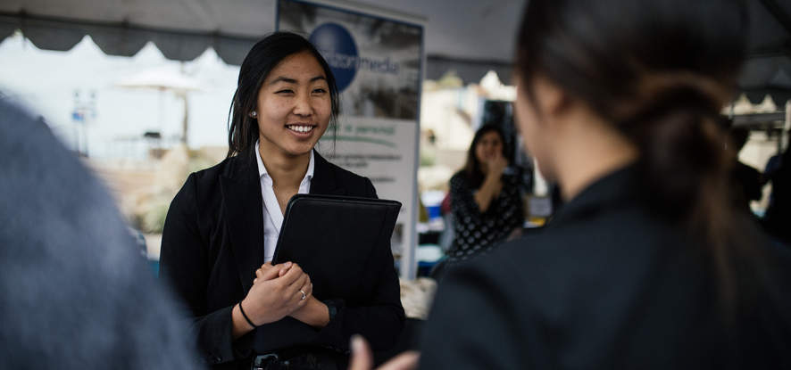 Female student holding a portfolio at a job fair on campus