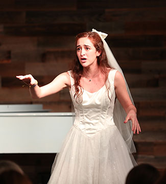 Student in white dress performing on stage