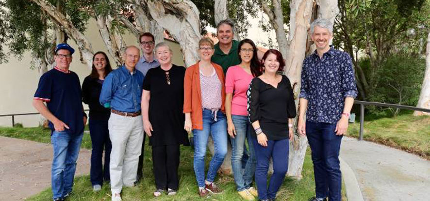Five professors stand in front of a tree