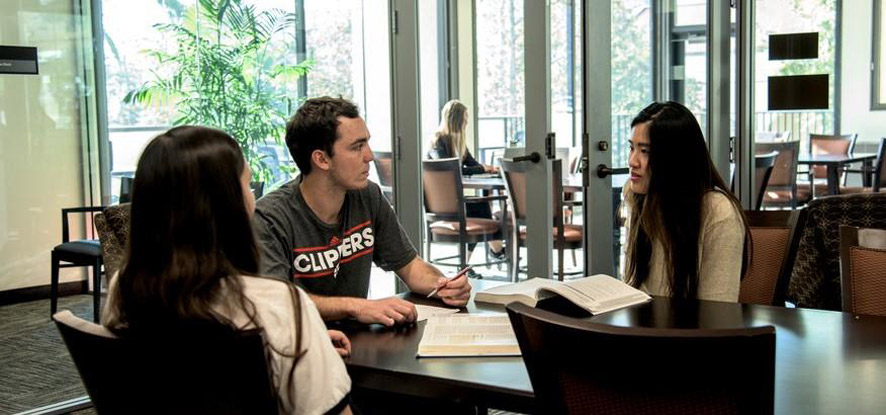 Three students gathered at a table inside the Student Success Center