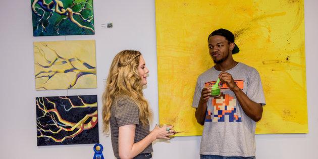 Seaver alums discussing their art in front of a yellow painting