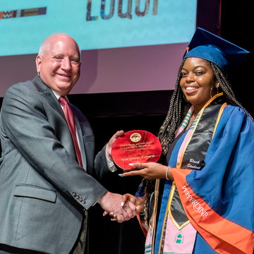 Naya Edwards accepts an award from Dean Michael Feltner