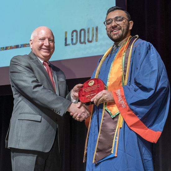 Sahej Bhasin accepting an award from Dean Michael Feltner