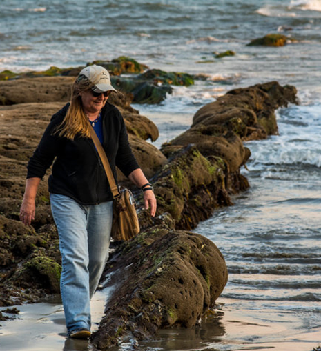 Dr. Karen Martin walks across rocks and tidepools on shore. 