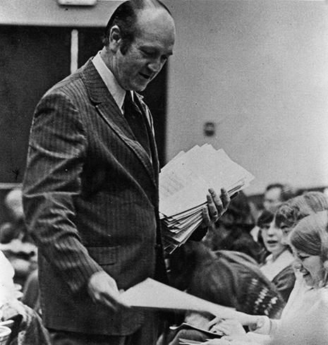 James Smythe looking down while distributing exam. 