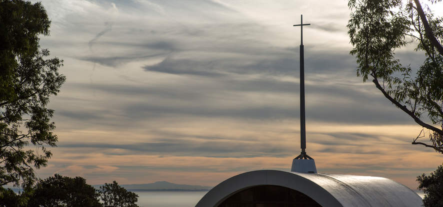 Top of Stauffer Chapel, cross structure, pictured against cloudy skies