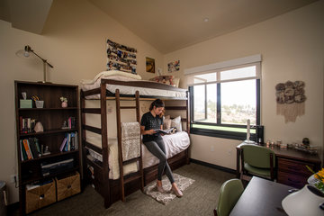 Student reading a book in her dorm room