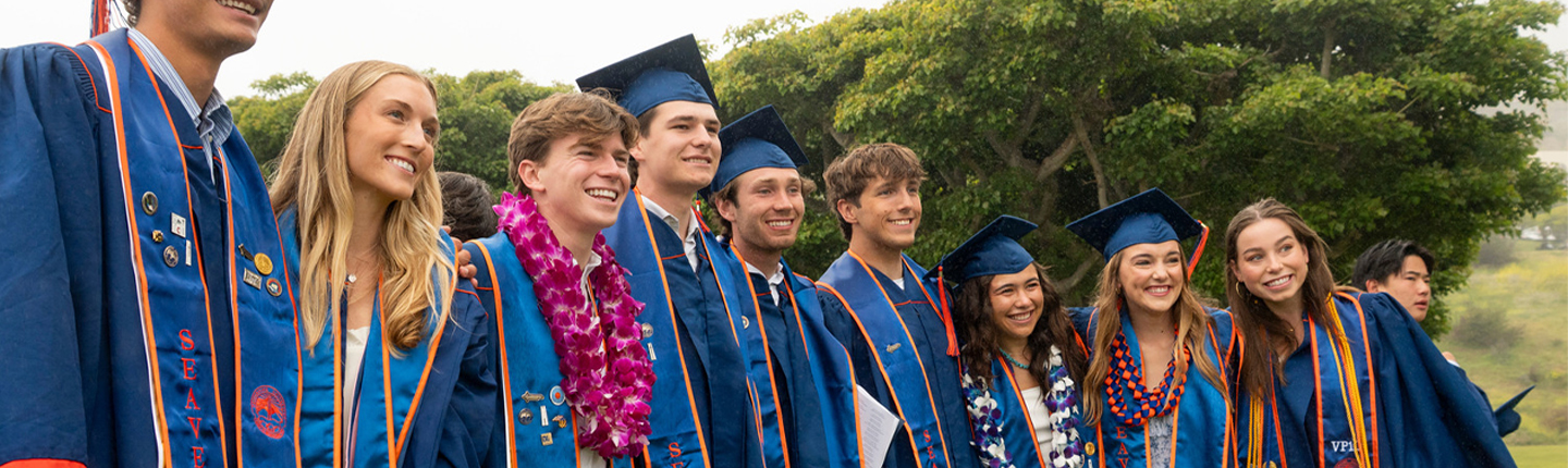 Students in cap and gown, smiling
